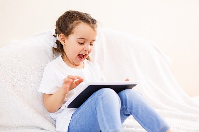 Little girl looking excited and watching at a tablet device